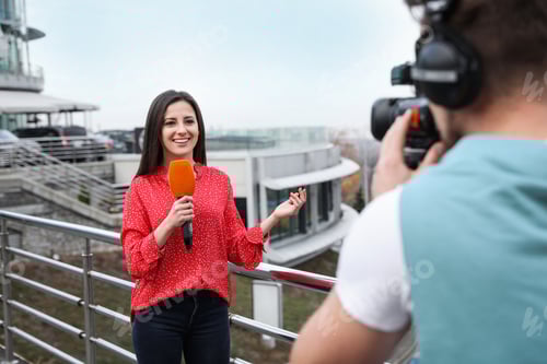 Preview: Young journalist and video operator working on city street