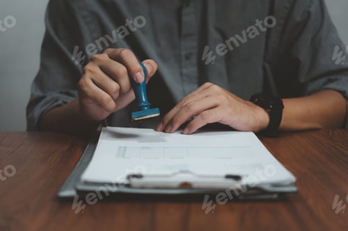 Preview: Man stamping approval of work finance banking or investment marketing documents on desk.