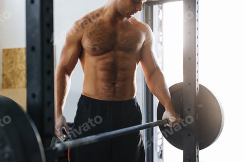 Preview: Unrecognizable sportsman holding a barbell, getting ready to lift weight