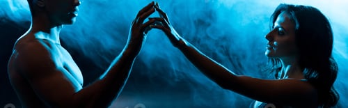 Preview: panoramic shot of young woman in bra touching hands with sexy muscular mixed race man on blue with