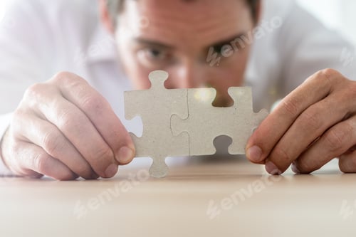 Preview: Businessman merging together two matching puzzle pieces