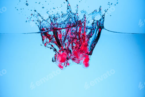 Preview: ice cubes with berries in water with drops, isolated on blue