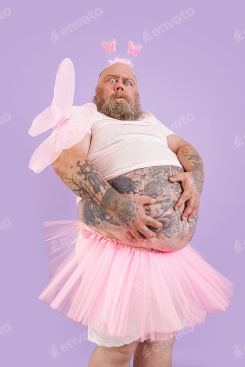 Preview: Surprised plump male person in fairy costume holds large tummy on purple background