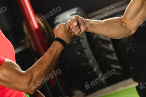 Preview: Two muscular men are making fist bump gesture during workout in the gym