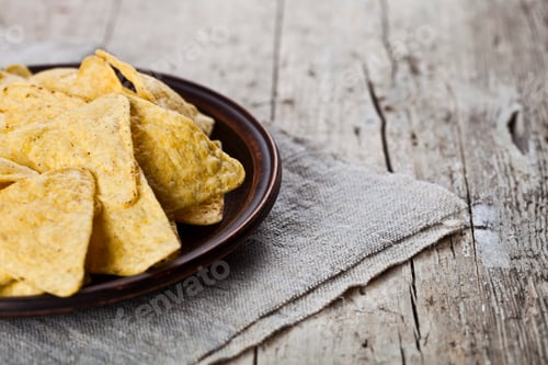 Preview: Mexican nachos chips on brown ceramic plate on linen tablecloth.
