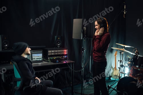 Preview: Recording songs in a music studio. Woman singer with headphones and sound producer.