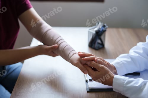 Preview: Doctor is examining the arm of a female patient who has been in an accident.