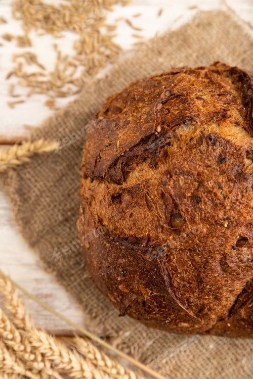 Preview: Fresh homemade golden grain bread with ears on white, top view, close up.