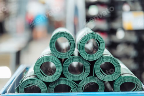 Preview: New rolled up yoga and fitness mats on a store shelf. Close view