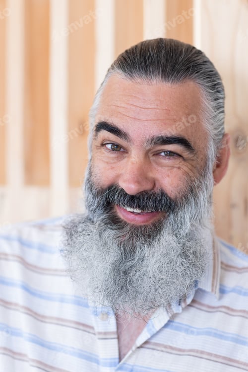 Preview: Smiling bearded senior man in striped shirt posing for portrait indoors