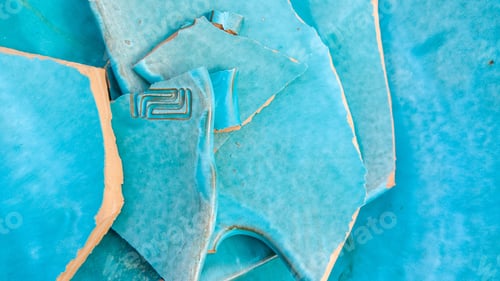 Preview: Overhead shot of a light blue broken ceramic plate lying on the ground