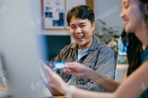 Preview: Two software developers are having fun while working together in the office. They are looking at a f