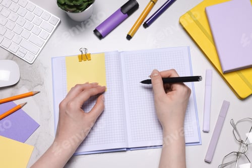 Preview: Woman with planner and stationery at light marble table, top view