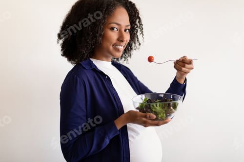 Vista previa: Feliz señora negra milenaria con gran barriga disfruta del embarazo, come ensalada