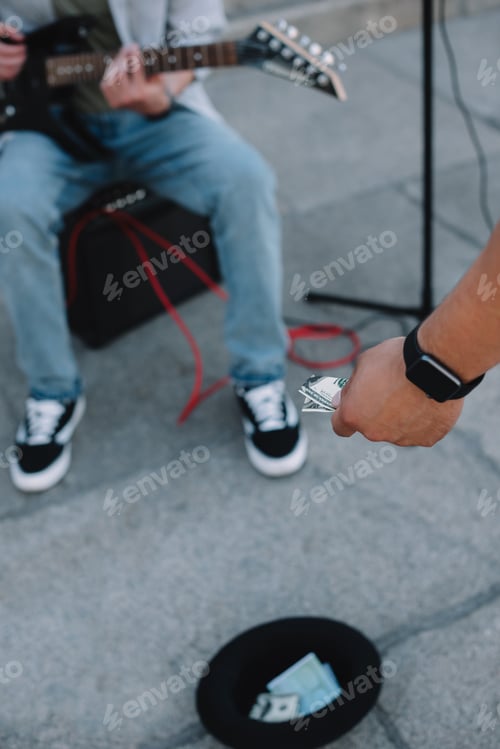 Preview: Passerby supporting street musician in city and putting money in hat on ground