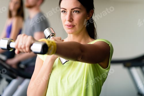 Preview: Beautiful woman doing exercises with dumbbell in gym. Girl is enjoying with her training process
