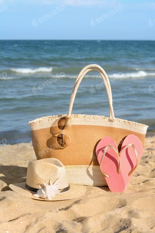 Preview: Stylish bag and other beach accessories near sea on sunny day