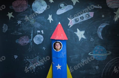 Preview: Portrait of girl in handmade space rocket in front of space themed chalk drawings