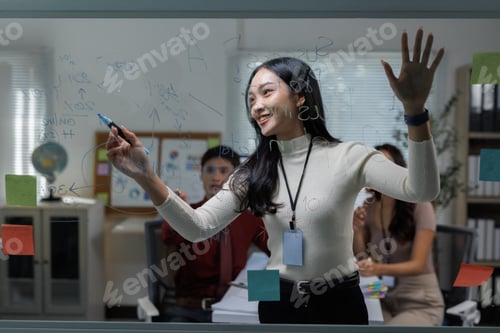 Preview: Businesswoman writing ideas on glass whiteboard during meeting
