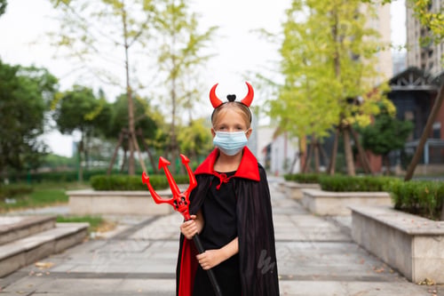 Preview: Happy kid in evil costume celebrating Halloween 2020 during coronavirus covid-19 pandemic