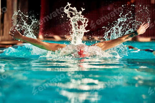 Preview: A man with a red cap swims in a blue pool, head-on shot