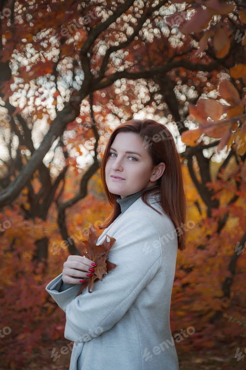 Preview: A cute redheaded woman in park on an autumn day
