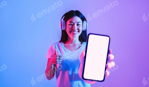 Preview: Music App. Happy Young Asian Woman Wearing Headphones Showing Big Blank Smartphone