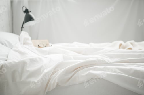 Preview: Selective focus of glasses on empty white bad and lamp