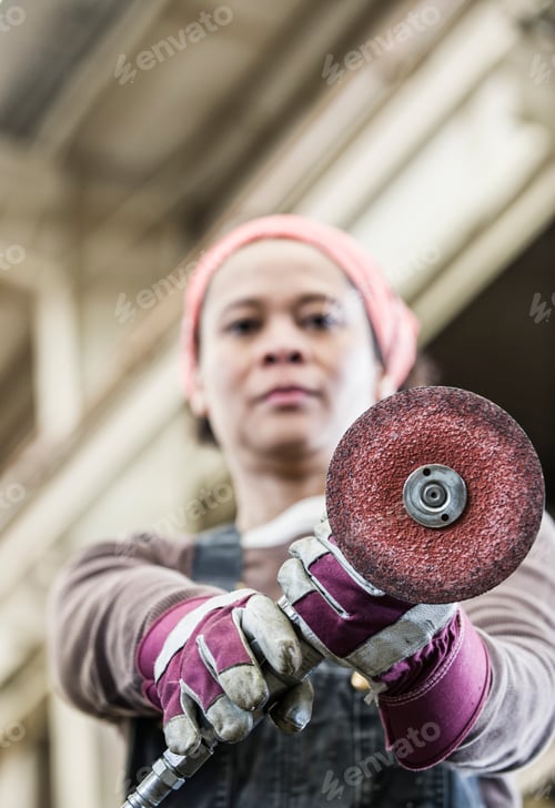 Preview: Black woman factory worker using a metal grinding tool in a sheet metal factory.