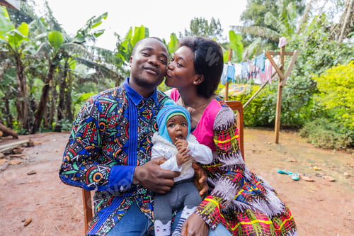 Preview: Wife gives husband a kiss on the cheek, husband holds newborn son, united and happy African family
