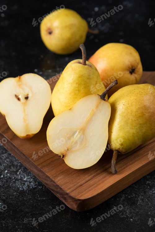 Preview: Wooden board of delicious yellow pears on black surface