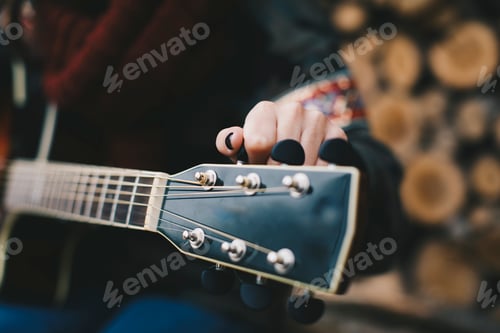 Preview: Young woman tuning guitar, close-up