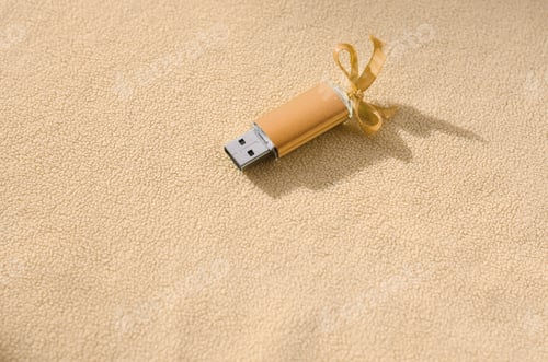Preview: Orange usb flash memory card with a blue bow lies on a blanket of soft and furry light orange