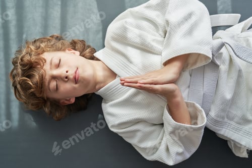 Preview: Boy in kimono lying on floor and doing namaste gesture
