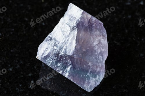 Preview: raw purple striped fluorite mineral on black