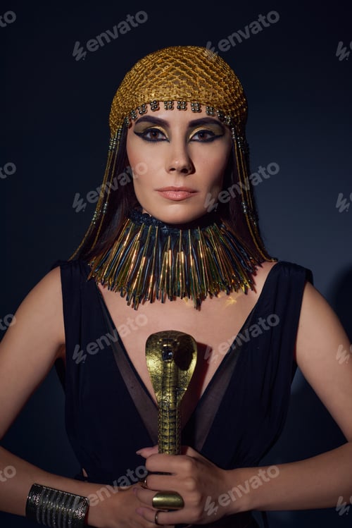 Preview: Portrait of woman in egyptian look and headdress holding crook in snake shape on blue background