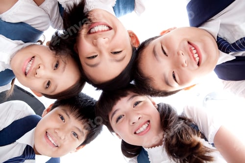 Preview: Cute schoolchildren huddling in a circle smiling happily