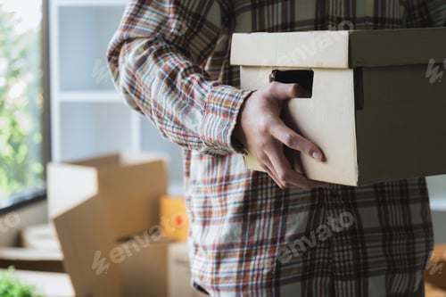 Preview: Close-up of a man with carton boxes moving into new home.