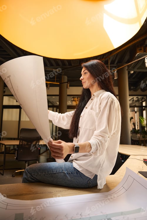 Preview: Woman in white blouse works with drawings in conference room