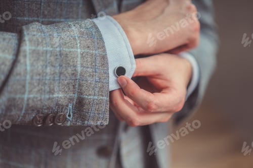 Man Fastening Cufflink on Gray Checked Jacket Sleeve