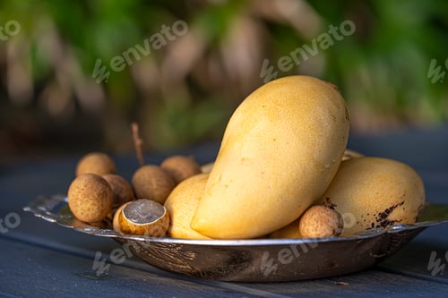Preview: Background with a plate of tropical fruits on a wooden table.