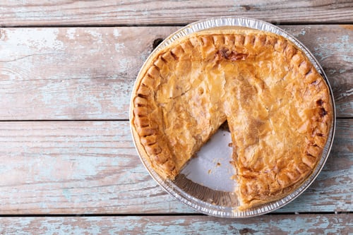 Preview: Directly above close-up shot of baked stuffed pie sliced in plate on wooden table