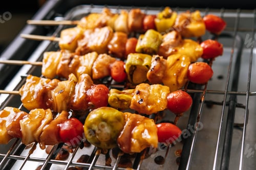Vista previa: BBQ grill with a variety of meats, complete with tomatoes and bell peppers.