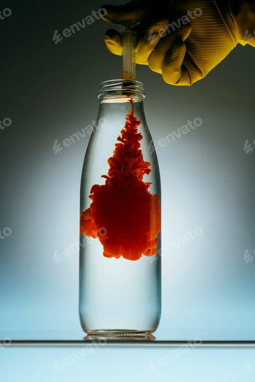 Preview: cropped view of person pouring red paint from syringe into bottle with water