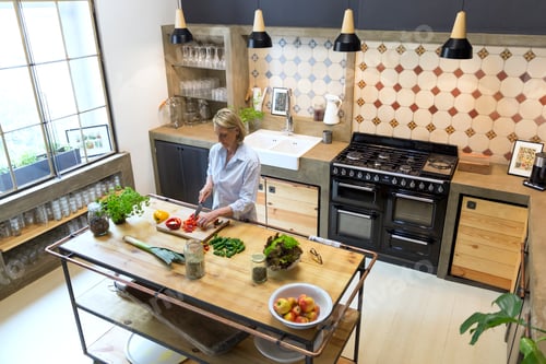 Preview: Mature woman chopping bell pepper in kitchen