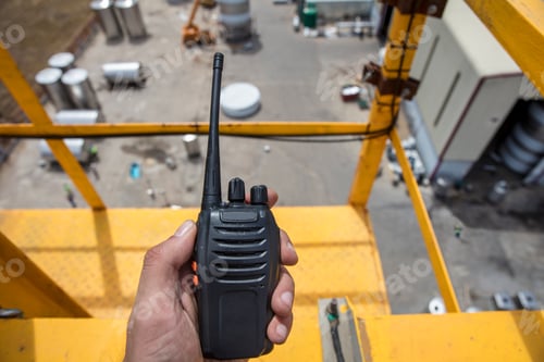 Preview: Hand holding walkie talkie on top of a crane on construction site