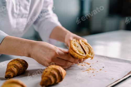 Preview: woman baker shows ready cut freshly baked hot crispy aromatic croissants and checks dough baking