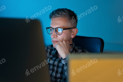 Preview: Focused Man Working at Computer in Office with Blue Light