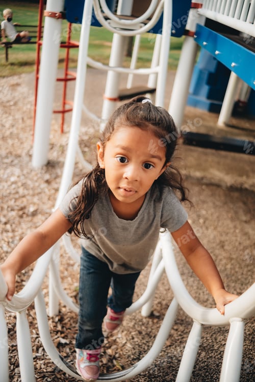 Preview: Mixed race preschooler at the park having fun on play equipment
