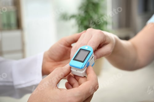 Preview: Doctor checking mature woman's pulse with medical device indoors, closeup